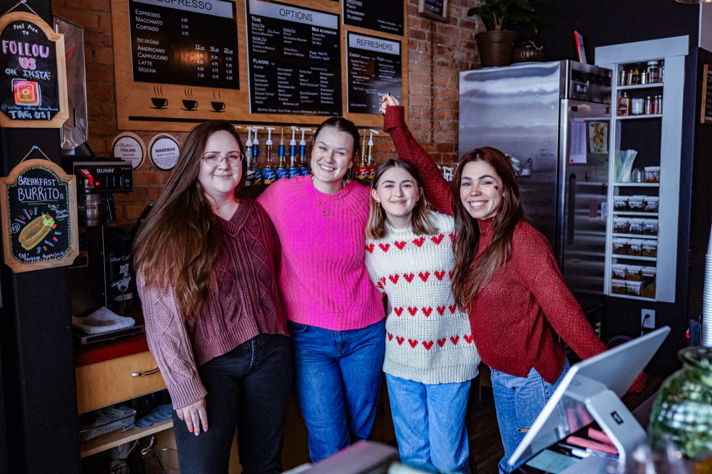 The Charro's Coffee House baristas behind the counter, smiling together in the shop