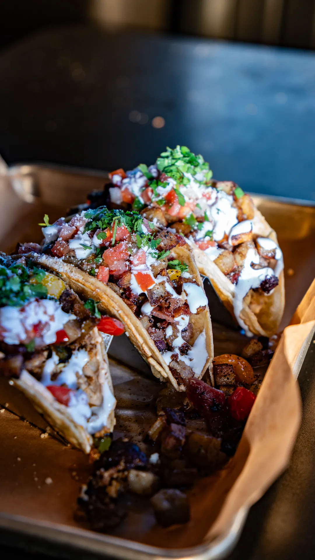 Three street tacos topped with cilantro, pico de gallo, cotija cheese, and crema from Mother Chorizo's Alley Taqueria