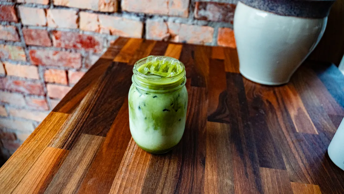 An iced matcha latte in a glass jar
