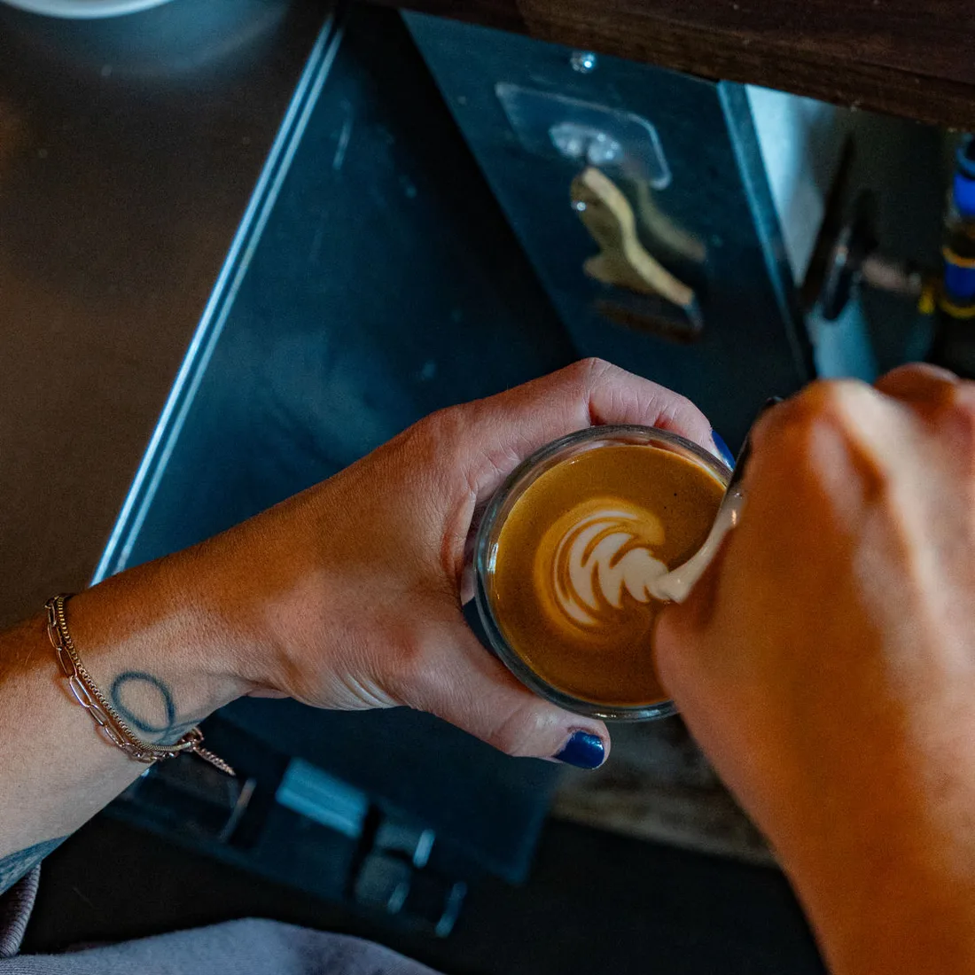 A Charro's barista pouring latte art into an espresso glass